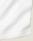 Close-up of a white linen table runner with white stripes embroidery