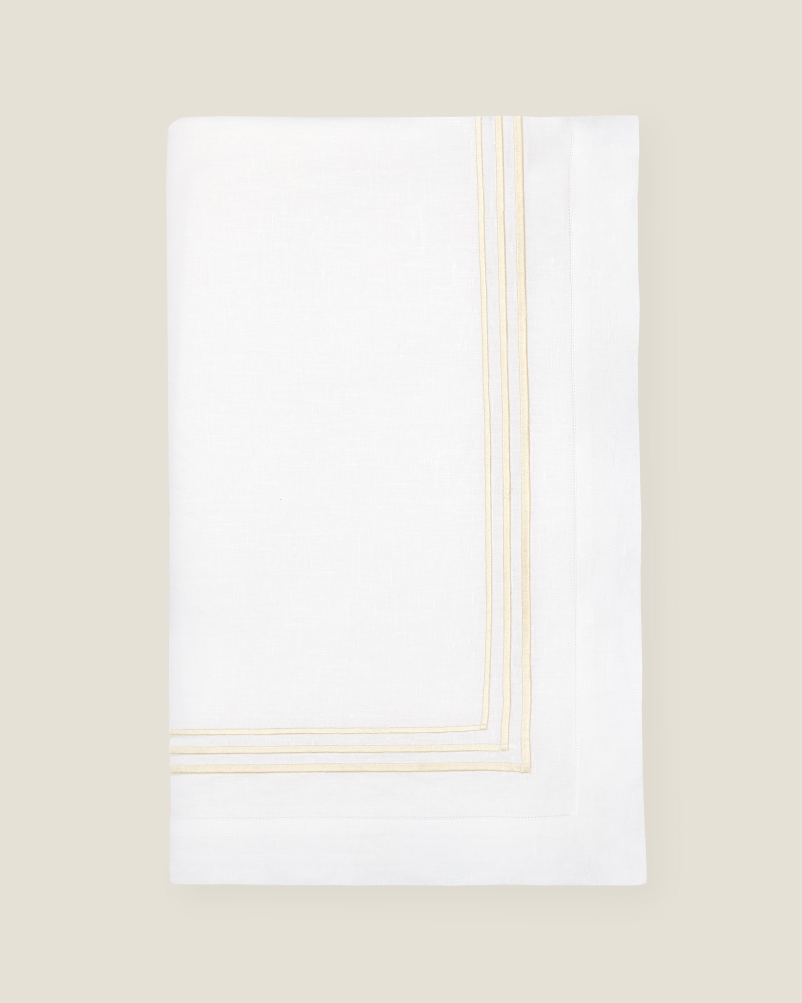 folded white tablecloth with beige stripes embroidery