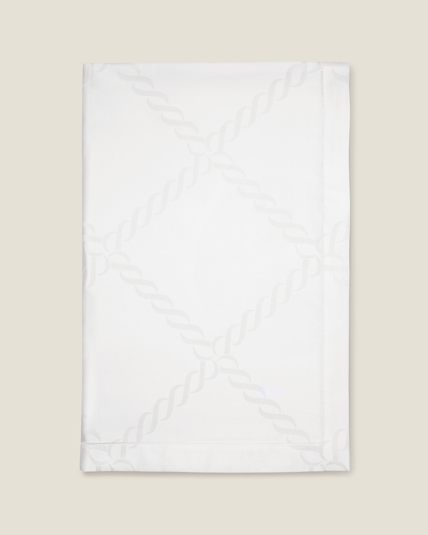 folded white tablecloth with braid motif pattern