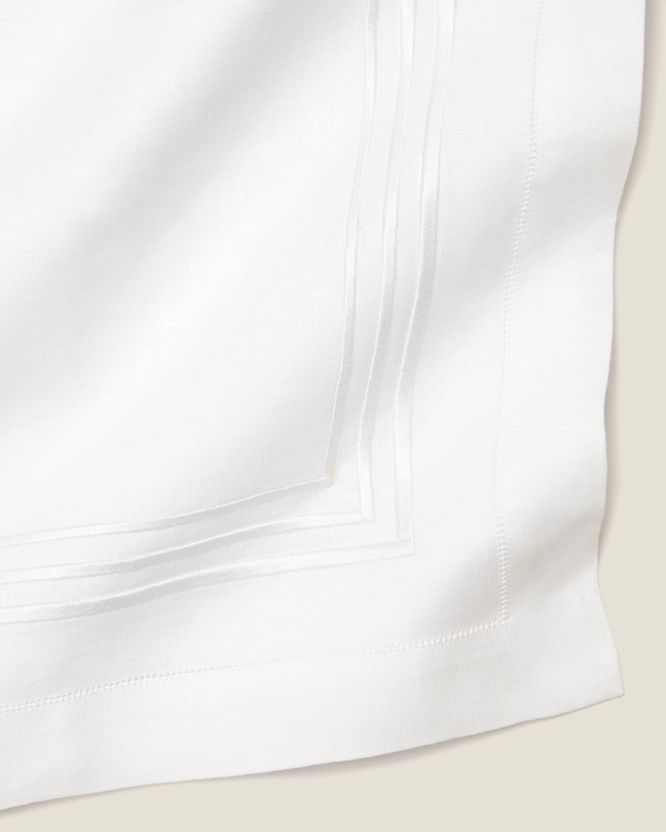Close-up of a white linen table runner with white stripes embroidery